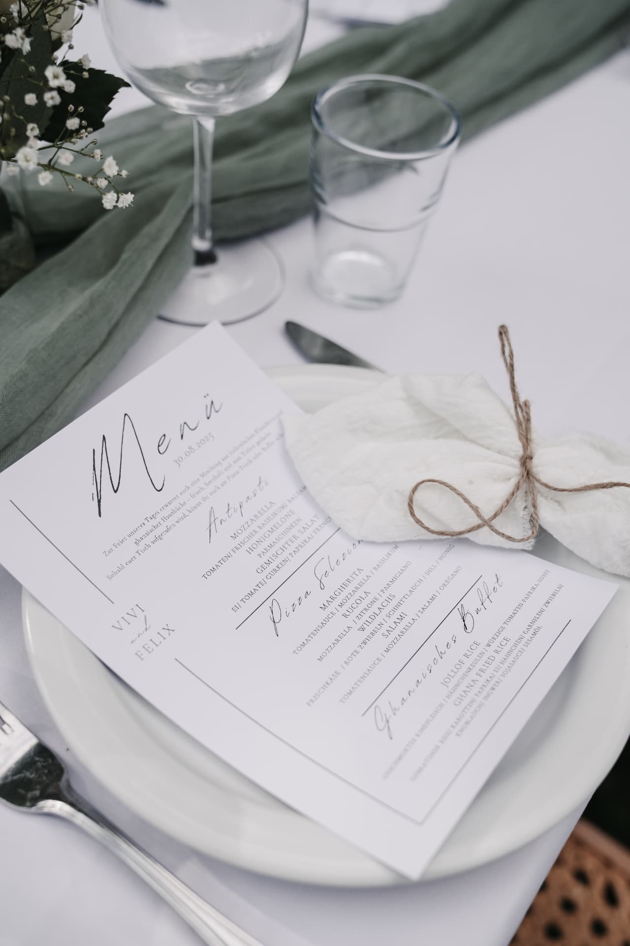 Menükarte mit Antipasti, Pizza Selezione und Ghanaischem Buffet auf weiß gedecktem Tisch