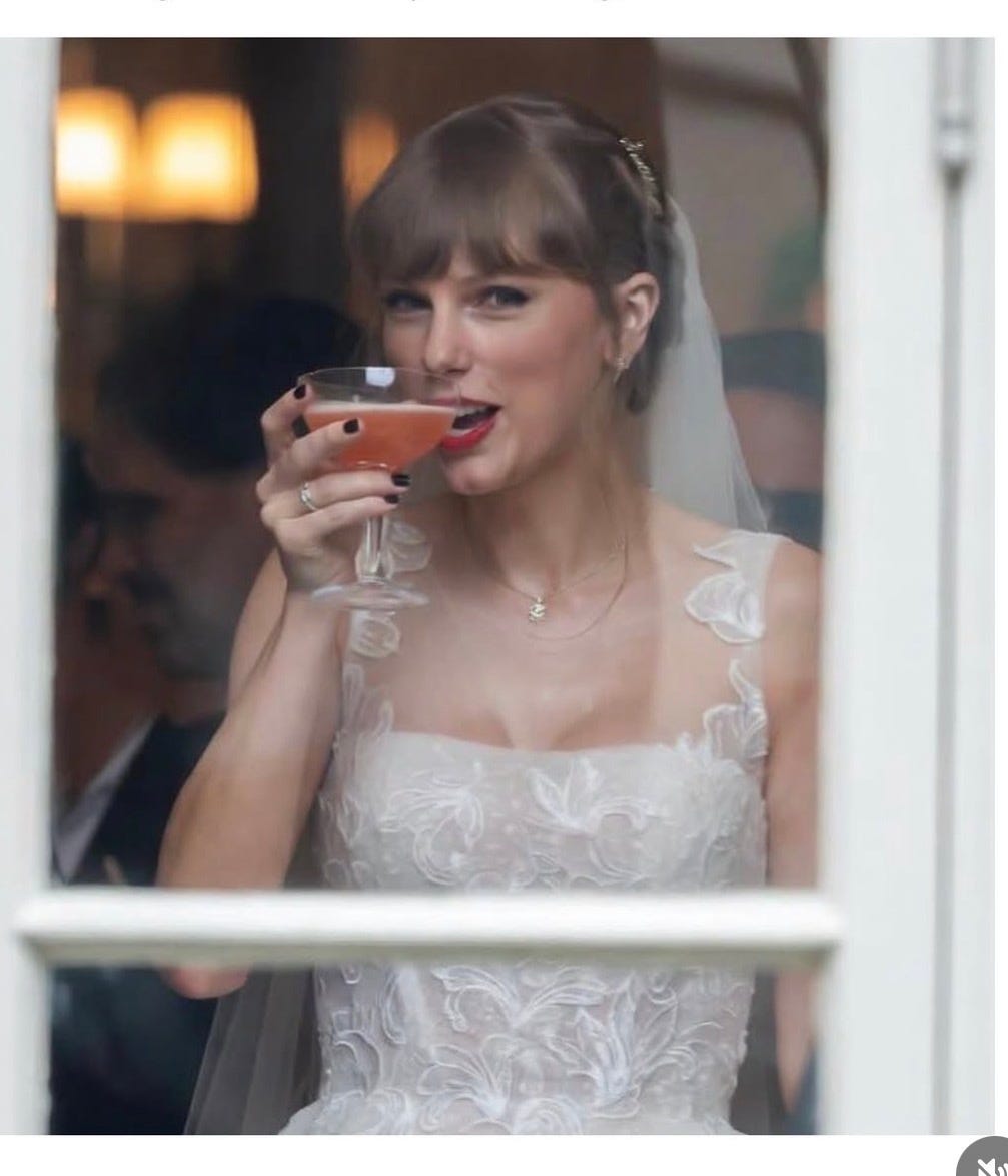 Taylor Swift im Brautkleid mit Schleier hinter einer Fensterscheibe, ein Glas mit rosafarbenem Cocktail in der Hand, Szene aus dem Musikvideo „I Bet You Think About Me“