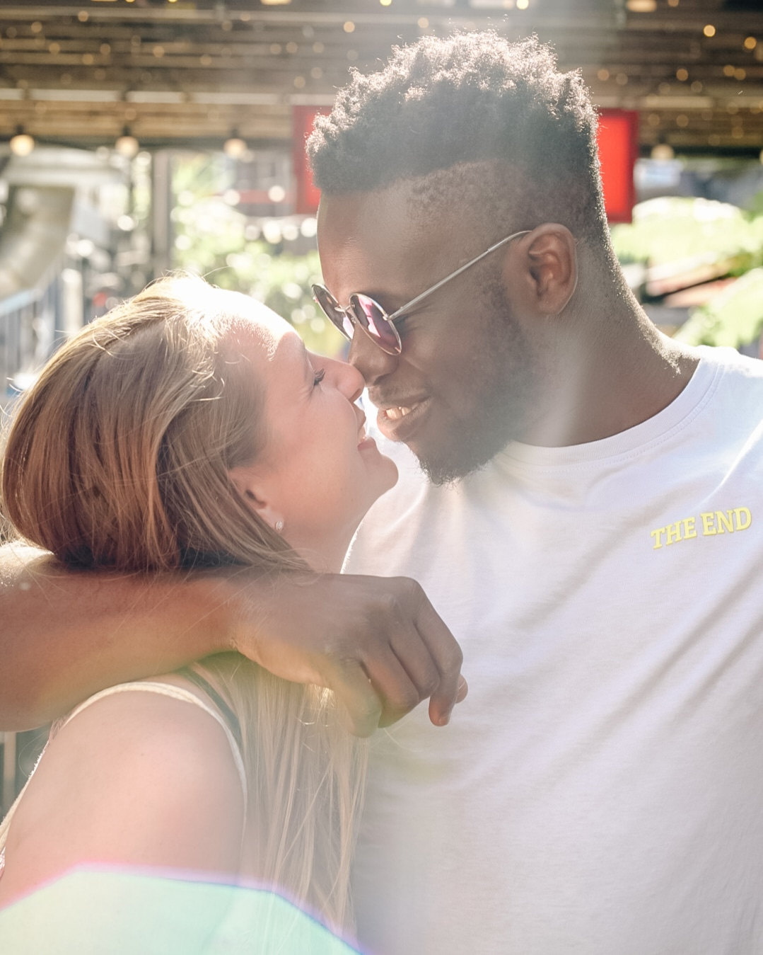 Paar im Profil im warmen Gegenlicht, er hat den Arm um ihre Schultern gelegt – Liebe und Commitment in einer langfristigen Partnerschaft.