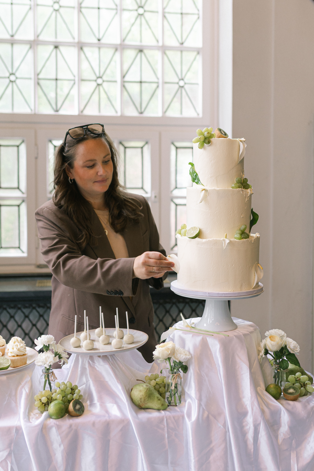 Vivien Opoku stylt eine mehrstöckige Hochzeitstorte mit Früchten und Blüten